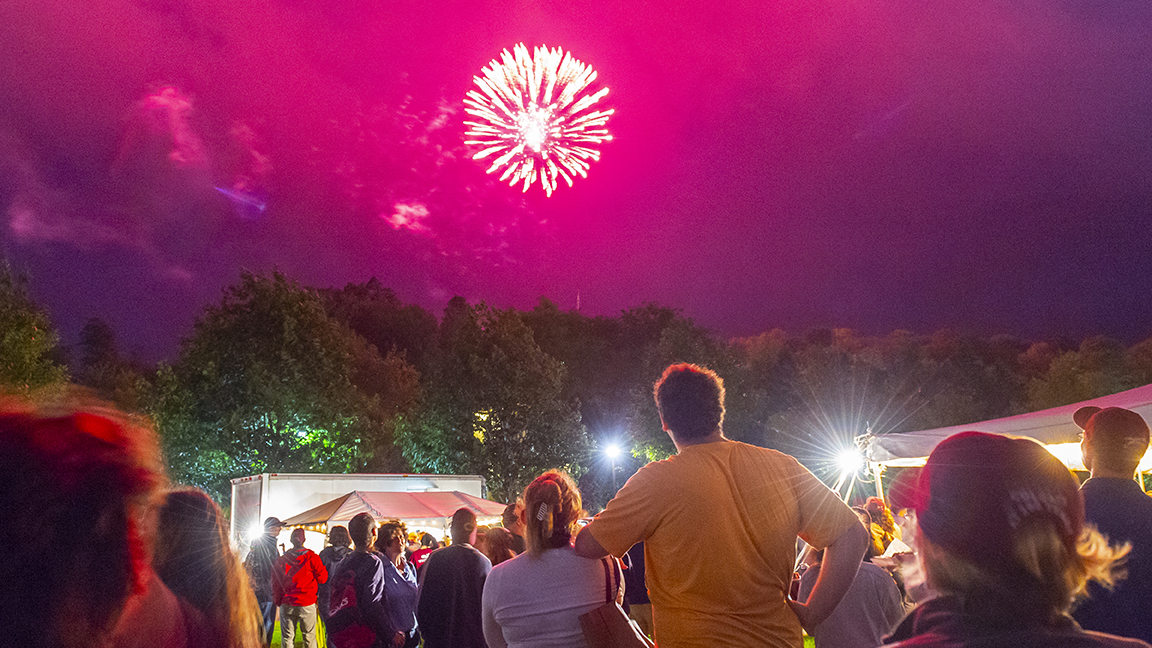 Attendees watch fireworks blossoming over the hill