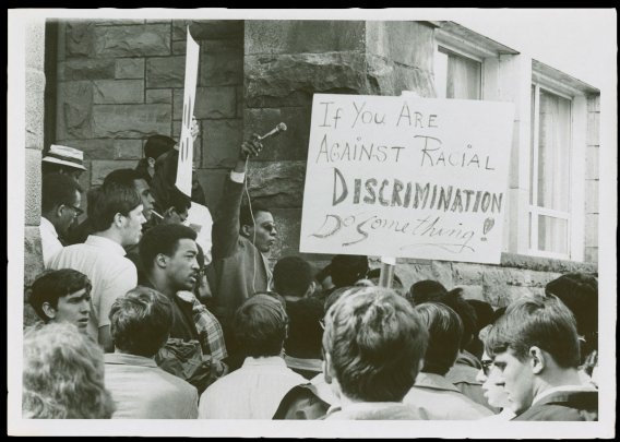 Students with protest signs reading "If you are against racial discrimination, Do Something!"